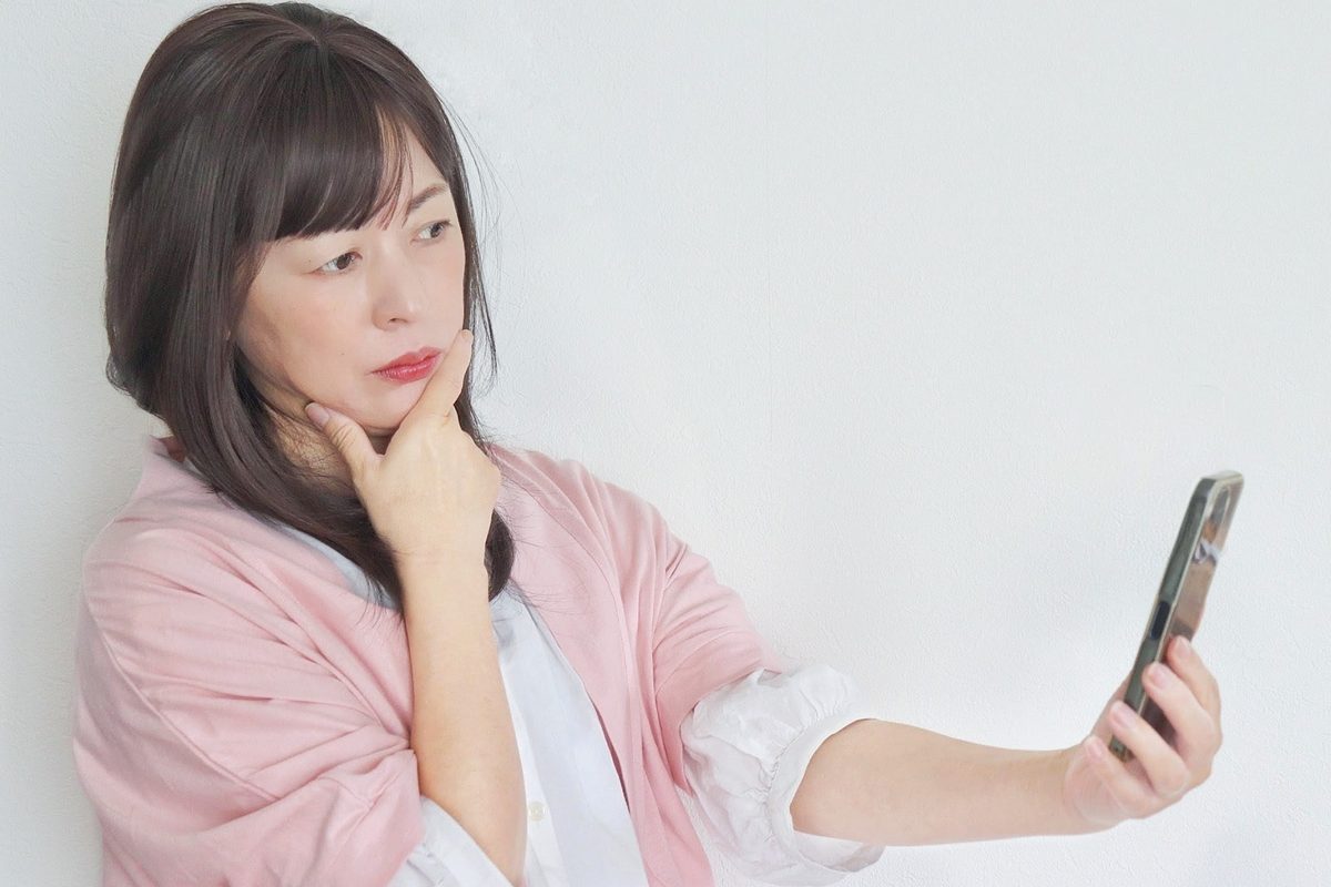 スマホを見て困っている50代女性
